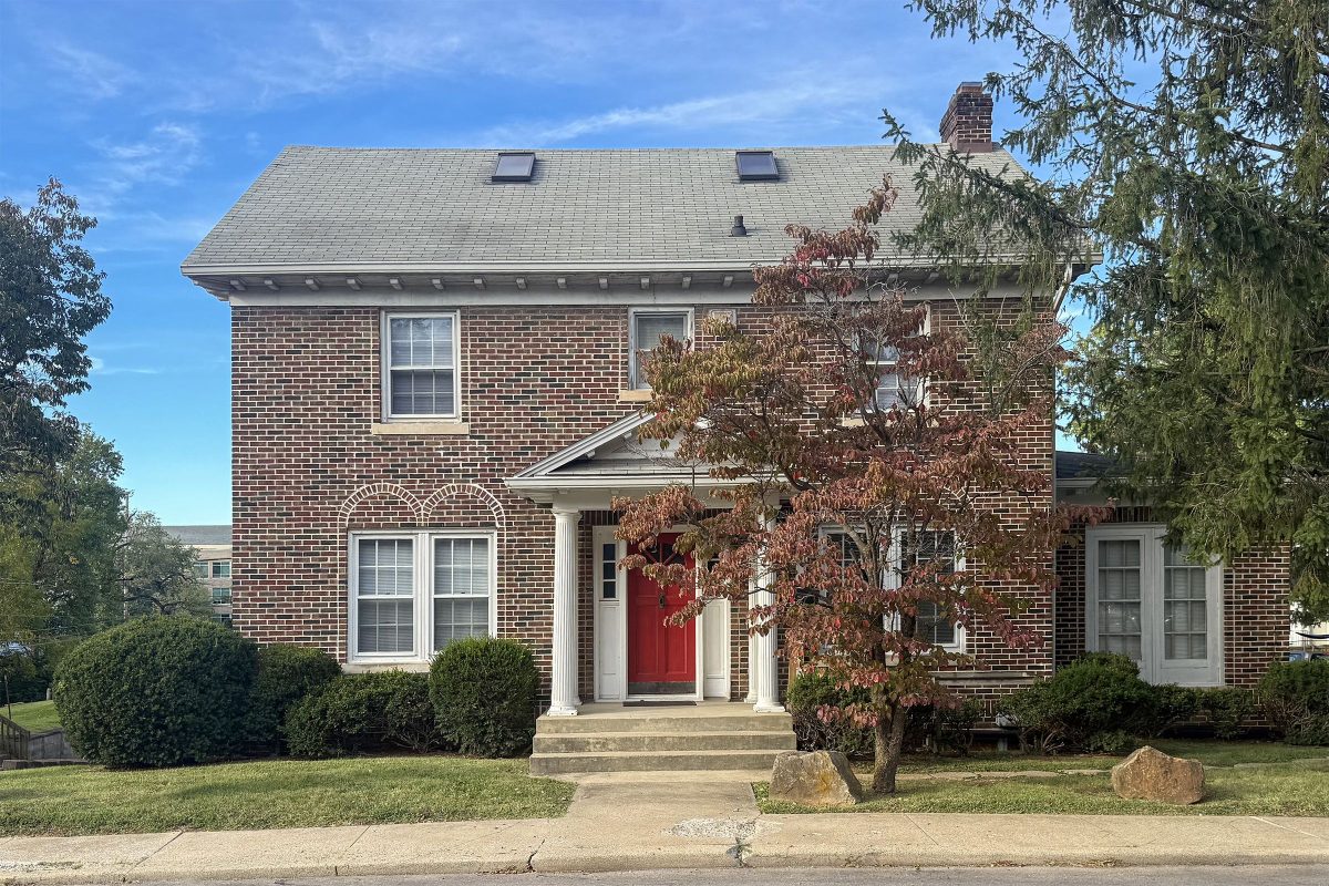 Front of 1331 E Atwater Ave, a brick house in Bloomington, IN, with a red door and a dogwood and evergreen at right